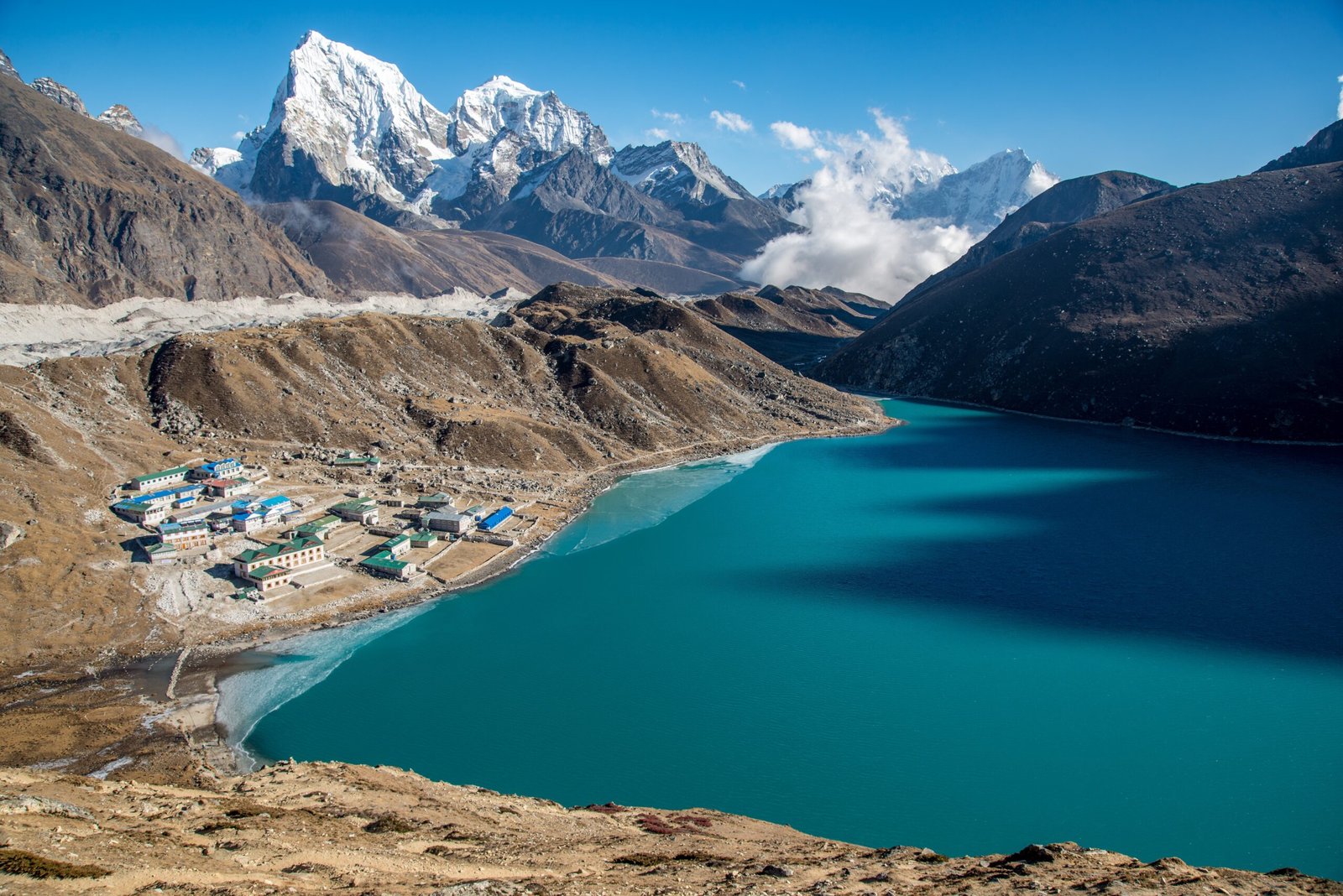 A high shot of a small town near a blue body of water surrounded by beautiful mountains.